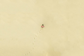 top aerial view of young lonely man walk in desert on the sand texture. lost concept