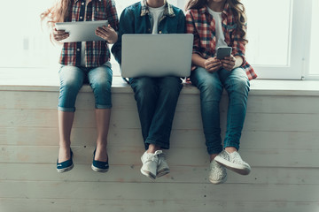 Kids Use Wireless Technology Sitting on Windowsill