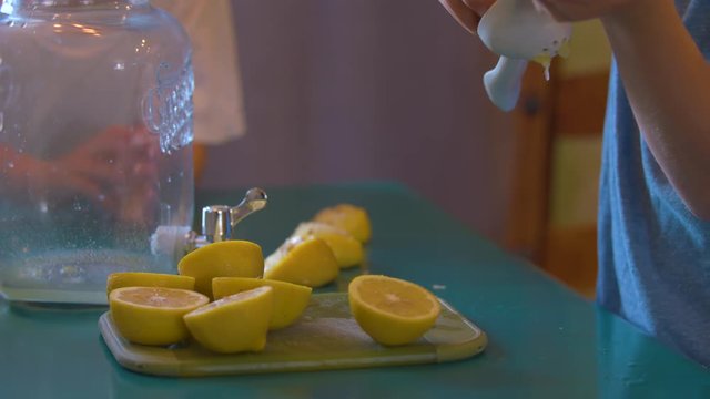 Boys Squeezing Lemon Halves into a Jar to make Lemonade
