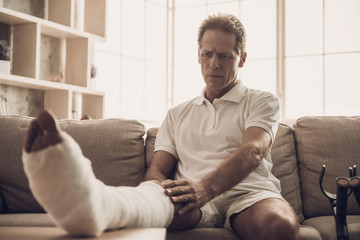 Portrait of Man With Fractured Leg Sitting On Sofa