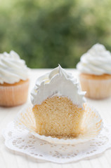 Vanilla cupcake cut in half on a wooden table.