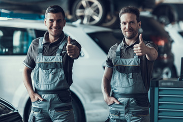 Two Handsome Happy Auto Mecanics Keeping Thumbs up