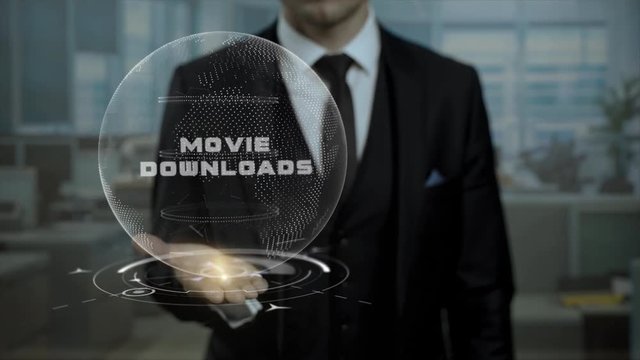 Executive dealer presenting strategy Movie Downloads using hologram. Entrepreneur in black suit holding cyber Earth with words on his hand.