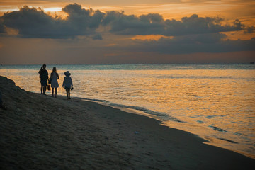 A family taking a beach walk against a golden sunset, Zanzibar, Tanzania 