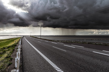 Dramatic sky over curved causeway in denmark