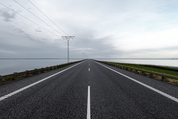Fototapeta na wymiar Long straight causeway with power line in Denmark