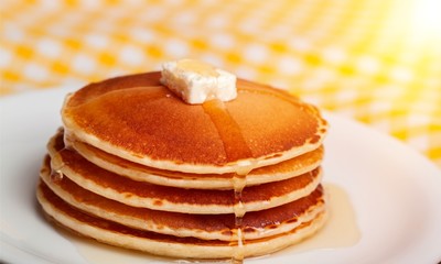 Stack of Small pancakes in syrup on background