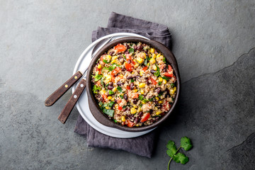Mexican black bean corn quinoa salad in clay bowl top view, copy space