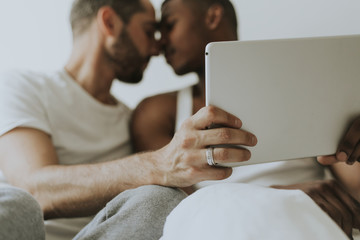 Gay couple using a tablet in bed