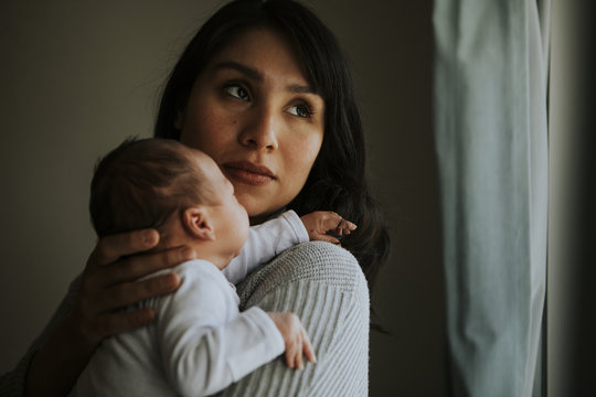 Mother holding her baby indoors