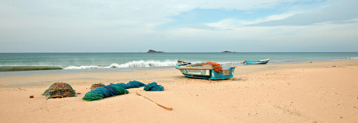 Nets, traps, woven baskets, and ropes next to fishing boat on Nilaveli beach in Trincomalee Sri Lanka