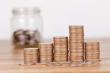 Stack of coins on wooden desk for saving money concept