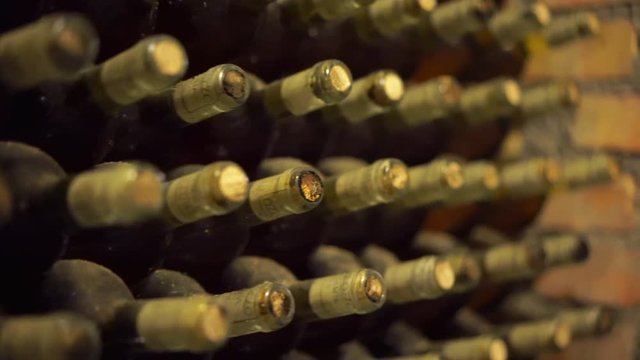 Old and dusty wine bottles in a wine cellar. Production of wine. Dark cellars with collectible red wine. 4K (UHD).