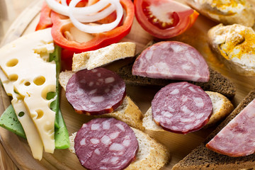 Breakfast table with cheese sandwiches, sausage, vegetables, hard boiled eggs and fruits
