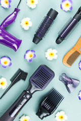 Hairdressing tools with flowers on blue wooden background