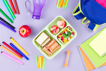 School concept flat lay. Kid backpack, lunchbox, water bottle, notebook, markers on wooden desktop