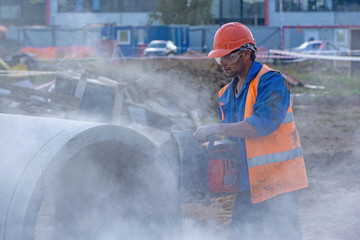 Worker at the construction site cuts the concrete ring for the well with a concrete cutter