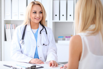 Doctor and  patient  discussing something while sitting at the table at hospital.  Medicine and health care concept