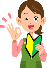 初心者マークを左手に持ち、右手でOKのサインを示す女性　エプロン
