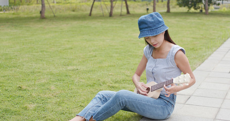 Fototapeta premium Woman playing ukulele at city