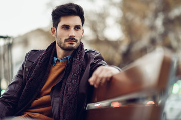 Thoughtful young man sitting on an urban bench.