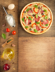 pizza and food ingredients at wooden table