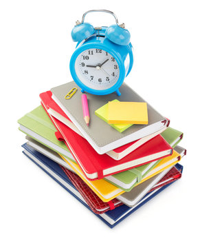 notebooks and alarm clock at white background