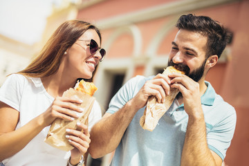 Young couple is eating sandwiches and having a great time