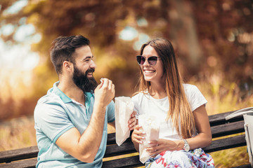 Young couple in park eating popcorn on beautiful sunny day