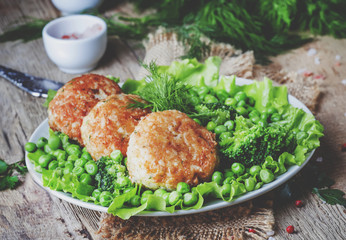 Fish cutlets or meatballs from cod and pike perch with a garnish of green peas and broccoli, rustic...