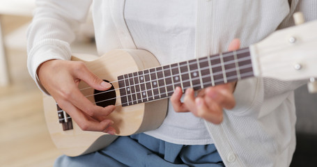 Woman play song on ukulele at home