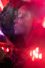 Young girl with glasses with trendy fur coat on neon lights