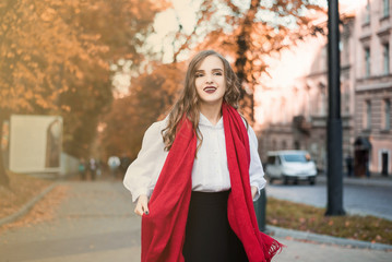 Fototapeta premium Street portrait of young beautiful woman wearing stylish classic clothes. Model looking up. Female fashion concept. French style. Parisian woman in old fashioned red scarf.