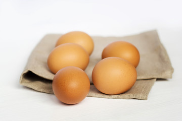 Brown chicken eggs on burlap on a white background