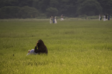 Pretty, cheerful girl sitting on green grass