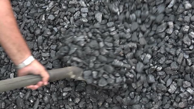 The worker rakes a pile of coal with a shovel