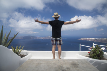 Happy man on vacation enjoying Santorini looking at the famous view of Caldera.