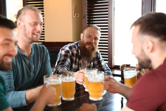 Friends clinking glasses with beer in pub