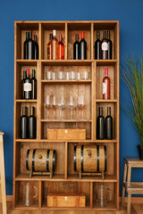 Wooden storage stand with wine bottles and glasses indoors