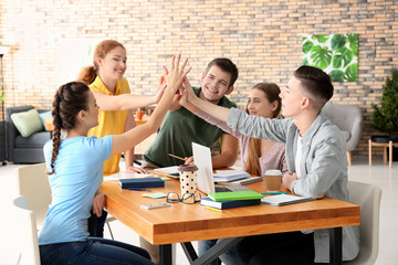 Group of teenagers giving high five indoors