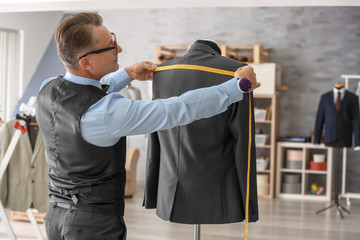 Tailor taking measurements of jacket on mannequin in atelier
