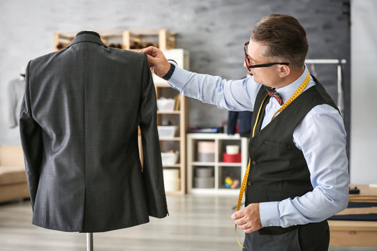 Mature man checking jacket on mannequin in atelier