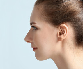 Young woman on grey background, closeup. Hearing problem