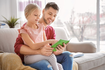Little girl with father doing homework at home