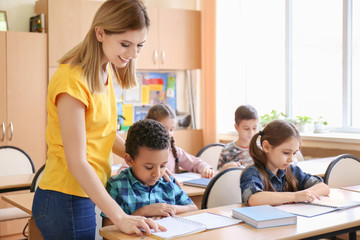 Female teacher helping boy with his homework in classroom at school