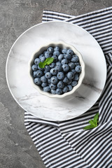 Dishware with juicy blueberries on color table, top view