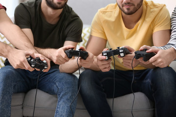 Young men playing video games at home, closeup