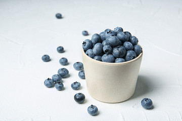Crockery with juicy and fresh blueberries on white table