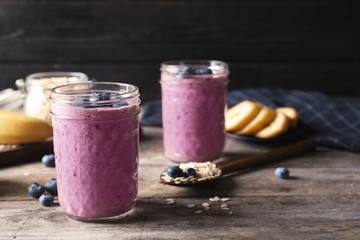 Jars with blueberry smoothies on wooden table
