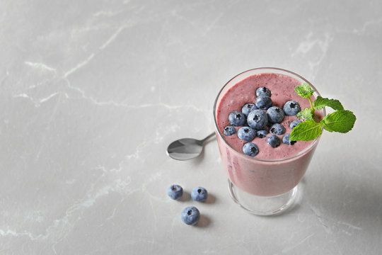 Glass with blueberry smoothie on light background. Space for text